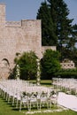 Wedding semi-arch stands near a brick wall in the garden in front of rows of chairs