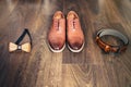 Wedding set of men's stylish shoes, wooden bow-tie and belt on a wooden background Royalty Free Stock Photo