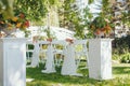 Wedding set up. Ceremony in the bosom of nature. White chairs with flowers set in the grass