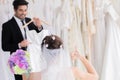 Wedding shopping lifestyle Concept, handsome groom help bride to choose beautiful wedding in fitting room studio, happy couple