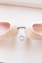 Wedding silver ring with black patterns between the bride`s shoes on a white background. Royalty Free Stock Photo