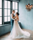 Wedding is a solemn day. Stylish young couple posing against the backdrop of a luxurious interior. The groom hugs the Royalty Free Stock Photo