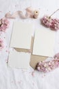Wedding stationery mock-up scene. Blank greeting cards, envelope on linen tablecloth background with pink blossoming Royalty Free Stock Photo