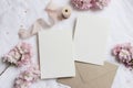 Wedding stationery mock-up scene. Blank greeting cards, envelope on linen tablecloth background with pink blossoming