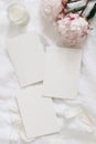 Wedding stationery, still life composition. Greeting cards mockup scene. Blank sheets of paper and pink peony flowers on