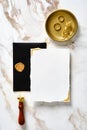 Wedding stationery top view. Wedding invitation card mockup, black envelope, wax seal stamp, golden rings on marble table. Luxury Royalty Free Stock Photo