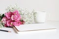 Wedding styled stock photo. Still life with pink roses, baby`s breath Gypsophila flowers, white cup, pencil and notebook