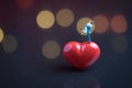 Wedding sweet romantic night concept, happy miniature couple holding and standing on red heart shape with soft low key dark