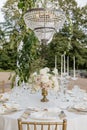 Wedding table with luxurious classic-style serving with bouquet of roses on terrace of restaurant.