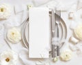 Wedding table setting with card near cream roses and white silk ribbons top view, mockup