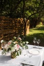 Wedding table setting decorated with fresh flowers in a brass vase. Wedding floristry. Banquet table for guests outdoors with a Royalty Free Stock Photo