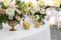 Wedding table setting decorated with fresh flowers in a brass vase. Wedding floristry. Banquet table for guests outdoors with a Royalty Free Stock Photo