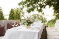 Wedding table setting decorated with fresh flowers in a brass vase. Wedding floristry. Banquet table for guests outdoors with a Royalty Free Stock Photo