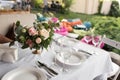 Wedding table setting decorated with fresh flowers in a brass vase. Wedding floristry. Banquet table for guests outdoors with a Royalty Free Stock Photo