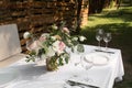 Wedding table setting decorated with fresh flowers in a brass vase. Wedding floristry. Banquet table for guests outdoors with a Royalty Free Stock Photo