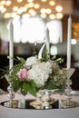 Wedding table setting is decorated with fresh flowers and white candles. Wedding floristry. Bouquet with roses, hydrangea and Royalty Free Stock Photo