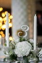 Wedding table setting is decorated with fresh flowers and white candles. Wedding floristry. Bouquet with roses, hydrangea and Royalty Free Stock Photo