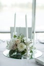 Wedding table setting is decorated with fresh flowers and white candles. Wedding floristry. Bouquet with roses, hydrangea and Royalty Free Stock Photo