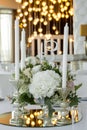 Wedding table setting is decorated with fresh flowers and white candles. Wedding floristry. Bouquet with roses, hydrangea and Royalty Free Stock Photo