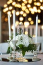 Wedding table setting is decorated with fresh flowers and white candles. Wedding floristry. Bouquet with roses, hydrangea and Royalty Free Stock Photo