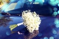 A wedding is a troublesome business: a delicate bouquet of the bride lies on the blue hood of a car, close-up, bokeh