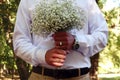 A wedding is a troublesome business: a delicate bouquet in the hands of the groom against the background of elegant clothes,