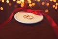 Wedding two gold rings on the table with red ribbon over celebration light bokeh
