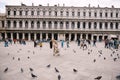 Wedding in Venice, Italy. The bride and groom kiss among the many pigeons in Piazza San Marco, against the backdrop of