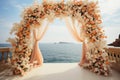 Wedding by the waves Peach floral arch, sea, and vases filled with fresh blooms