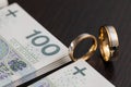 Gold wedding rings surrounded by a stack of Polish banknotes Royalty Free Stock Photo