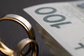 Gold wedding rings surrounded by a stack of Polish banknotes Royalty Free Stock Photo
