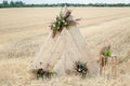 Wedding wooden arch decorated with a detailed flower arrangement in a golden, mown field. Rustic style Royalty Free Stock Photo