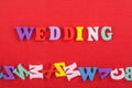 WEDDING word on red background composed from colorful abc alphabet block wooden letters, copy space for ad text. Learning english