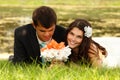 Wedding, young bride and groom in love lying on green grass