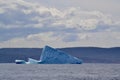 Wedge shaped iceberg under large cloud in bay outside St. John\'s