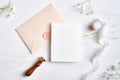 Wediing invaition card mockup, pastel pink weeding envelope, wax seal stamp, silk ribbon, flowers on stone table. Weeding