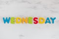 Wednesday word written with colorful letters on white marble stone background Royalty Free Stock Photo