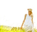 Weekend in the country. A beautiful young blonde woman standing in a meadow wearing a sunhat on a warm summers day. Royalty Free Stock Photo