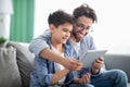 Weekend family leisure. Happy father and son using tablet computer, browsing internet online at home Royalty Free Stock Photo