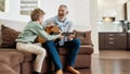 Weekend with grandpa. Cheerful mature man, grandfather playing guitar to his cute little grandson Royalty Free Stock Photo