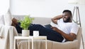 Happy african guy relaxing with digital tablet at home Royalty Free Stock Photo