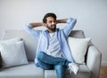 Relaxed Arab Guy Leaning Back On Couch With Hands Behind Head