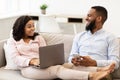 African american couple sitting on couch, using laptop and smartphone Royalty Free Stock Photo