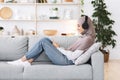 Weekend Pastime. Arabic girl relaxing at home with smartphone and wireless headphones