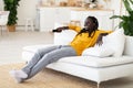 Weekend Pastime. Cheerful Black Guy Sitting On Couch And Watching Tv Royalty Free Stock Photo