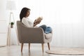 Weekend pastime. Relaxed african american woman reading book in comfortable armchair against window, free space