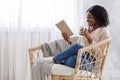 Weekend Pastime. Young Black Woman Relaxing In Armchair With Book And Coffee