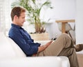 Weekend vibes on the sofa. a handsome man using his tablet while sitting on the sofa at home. Royalty Free Stock Photo