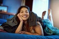 Weekends in this house are clothing optional. Portrait of a happy young woman lying under a pile of clothes on her bed. Royalty Free Stock Photo