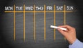 Weekly Calendar - female hand with chalk writing on blackboard Royalty Free Stock Photo